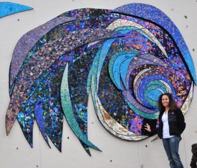 Mosaic artist Ali Mirsky in front of one of her large-scale murals.