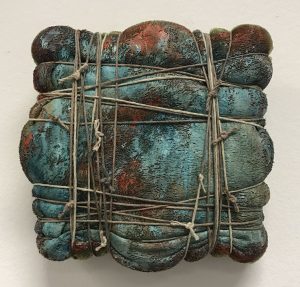 Lori Anne Boocks’ “Discrete Object No. 5 (Package to China),” just six inches square in size, resembles a misshapen parcel tightly tied up in string.